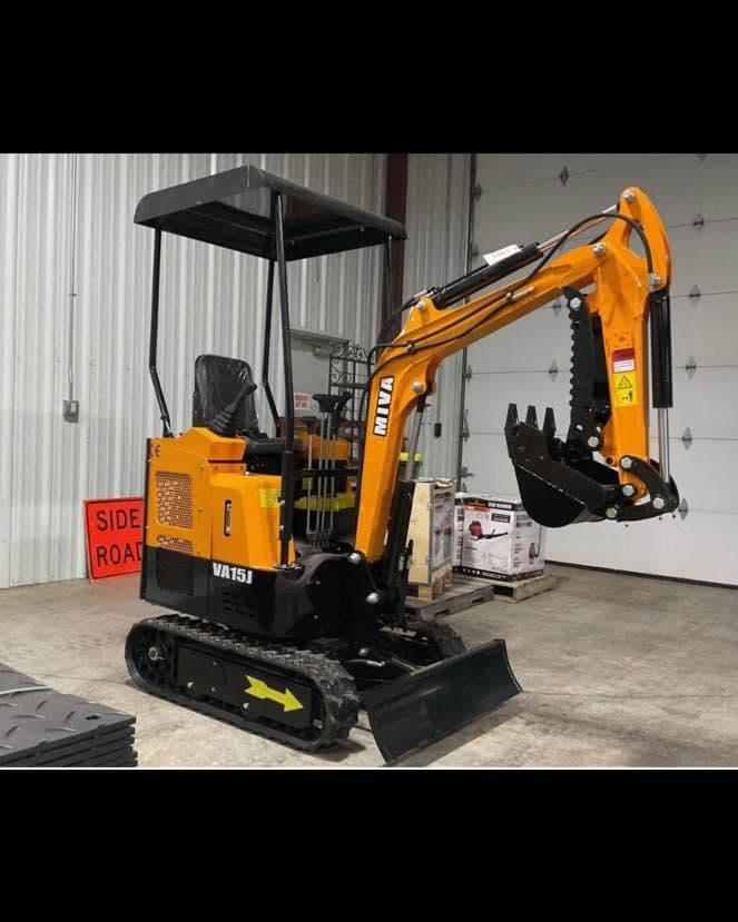 Mini excavator VAT15 displayed in a warehouse setting with orange and black color scheme.