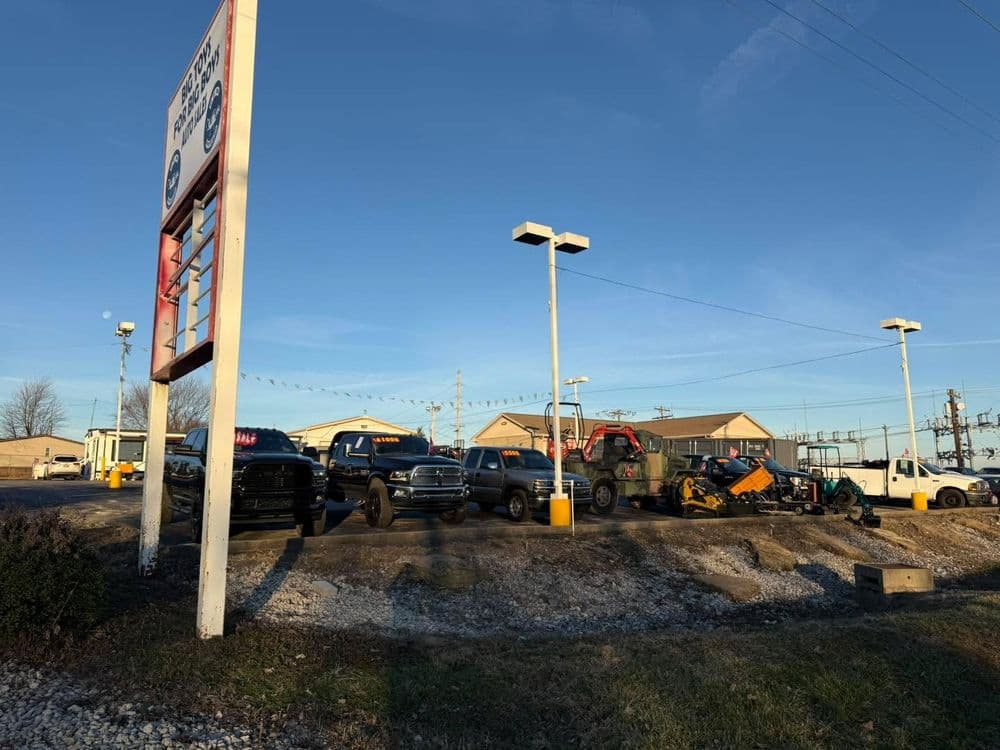 Trucks and equipment displayed at a vehicle dealership with clear blue skies.