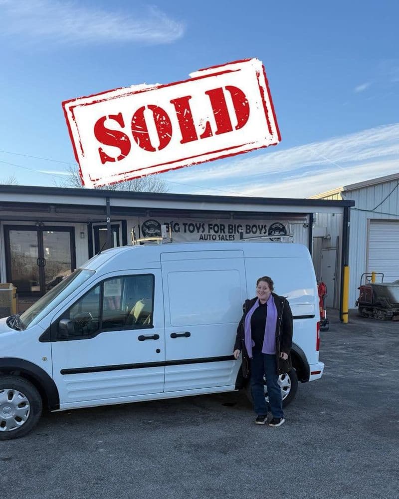 Woman standing next to a sold van outside an auto sales dealership.