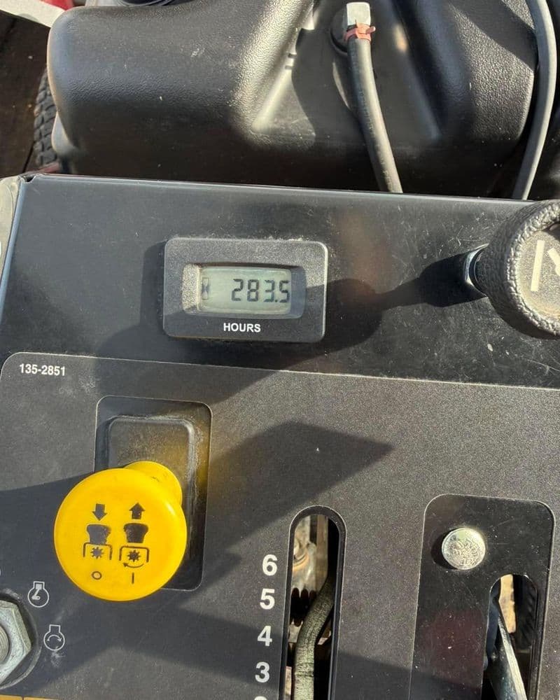 Hour meter showing 28.3 hours on a piece of equipment, featuring control levers and a ignition switch.