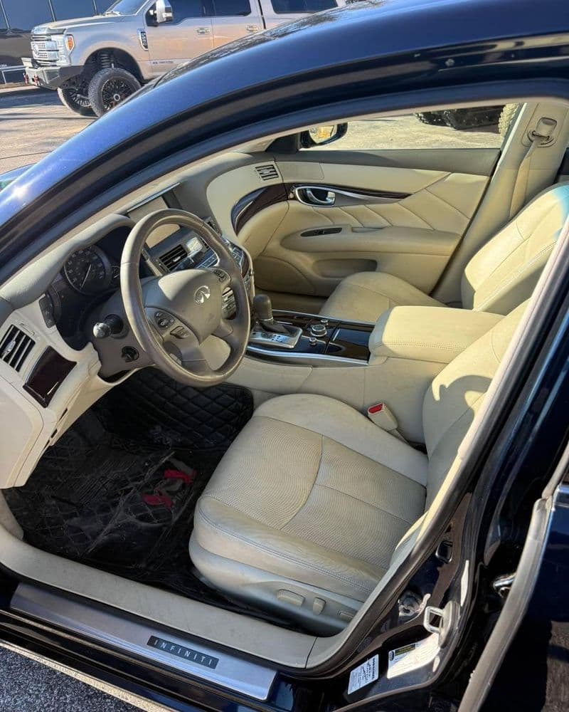 Interior view of a luxury Infiniti car with beige leather seats and modern dashboard features.
