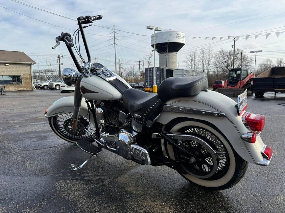 White motorcycle with chrome accents parked outdoors, featuring a classic design and long handlebars.