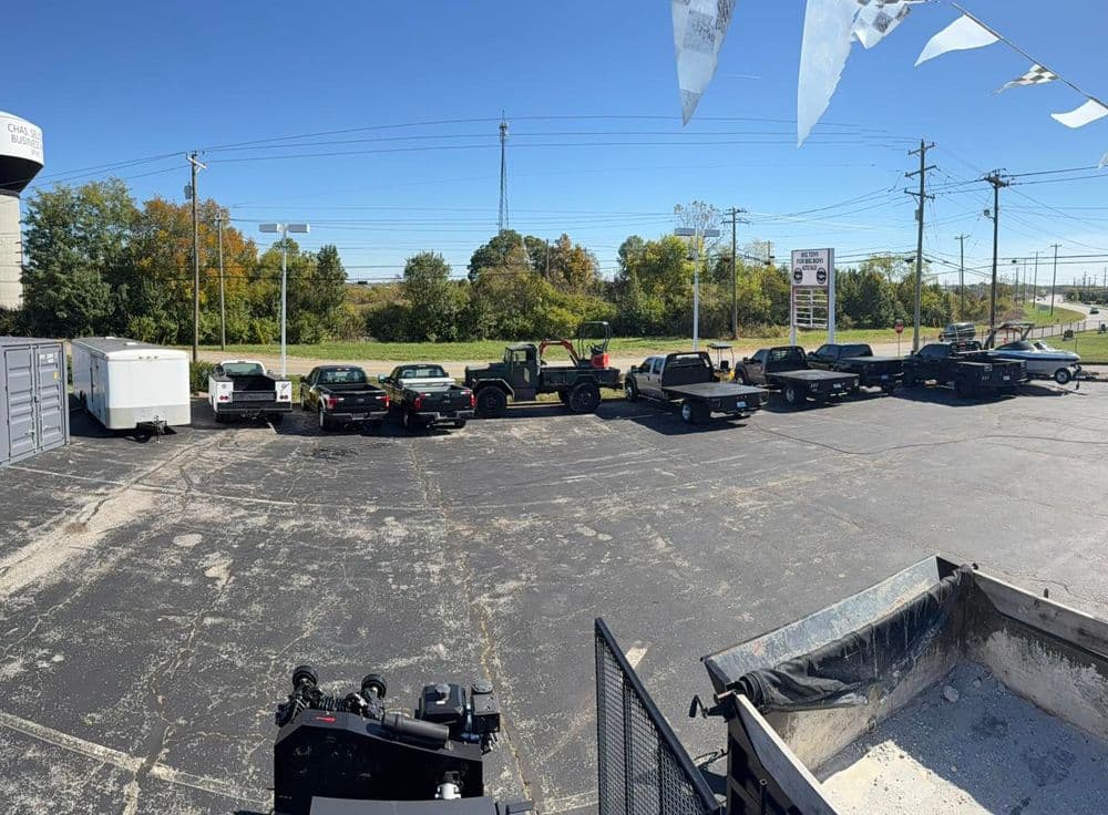 Used trucks and SUVs lined up for sale at a dealership on a sunny day.