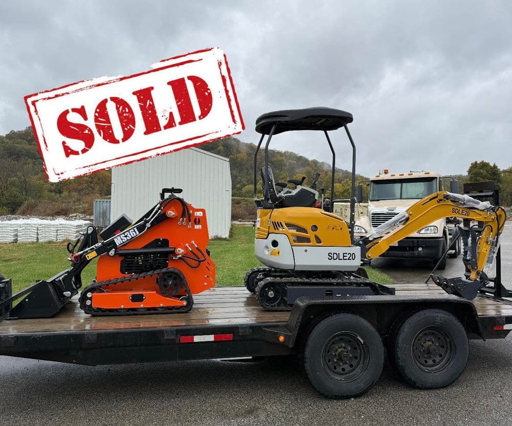 Sold construction equipment on trailer, featuring orange and yellow mini excavators.