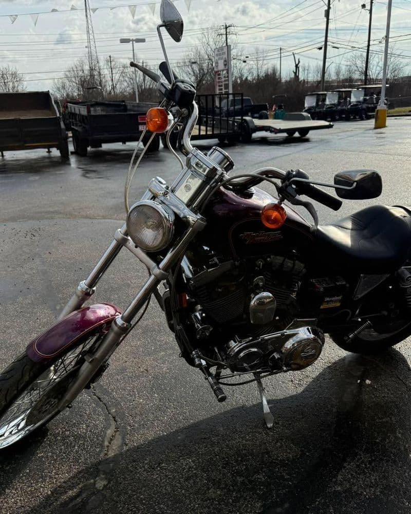 Purple motorcycle with chrome details parked outdoors on a sunny day.