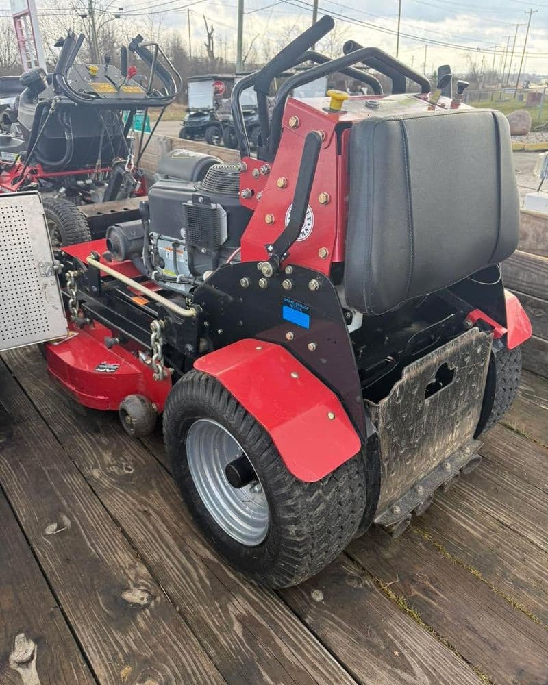 Red commercial riding lawn mower with a rear engine on a wooden trailer. Ideal for landscaping.