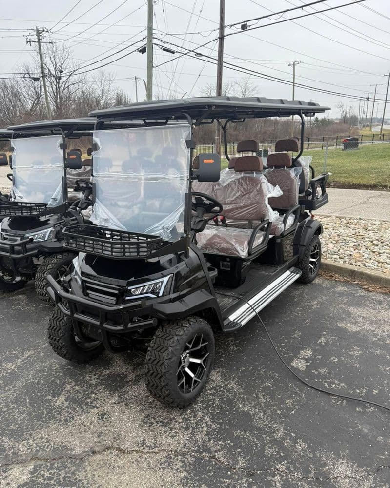Black golf cart with passenger seats displayed outdoors, parked on a paved surface.