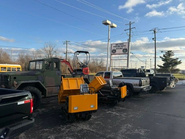 Snow plow and utility vehicles lined up at a dealership on a clear day.