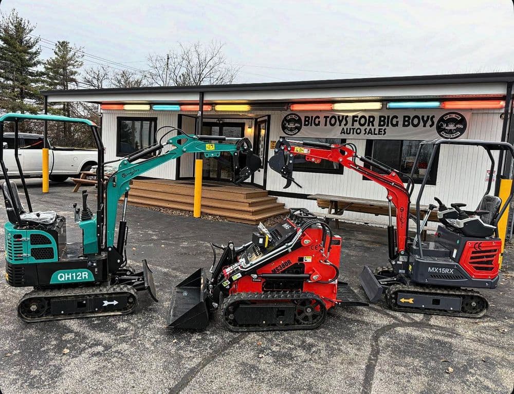 Three compact excavators in front of Big Toys for Big Boys dealership, showcasing construction equipment.