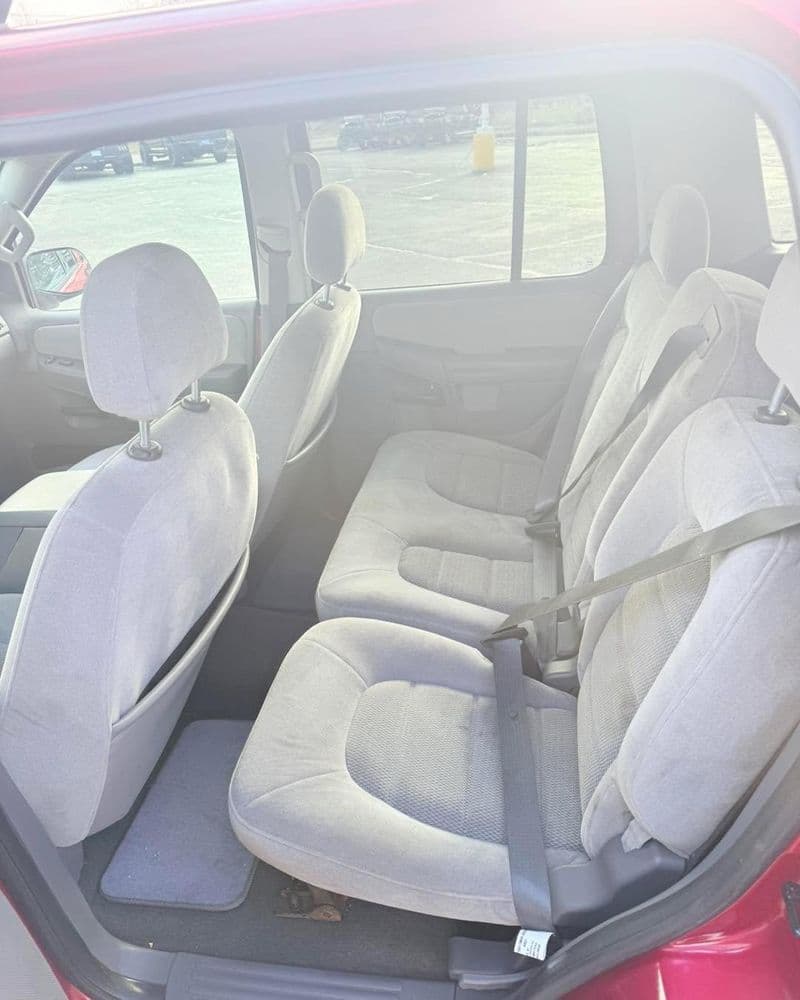 Interior view of a red SUV showcasing rear gray cloth seats with seat belts.