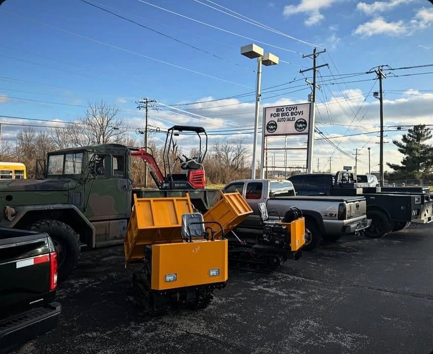 Various utility vehicles and equipment on display at a dealership with a clear blue sky.