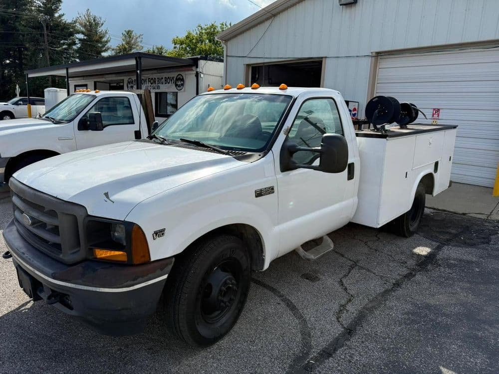 White Ford truck with utility bed parked in front of a service building. Ideal for work use.