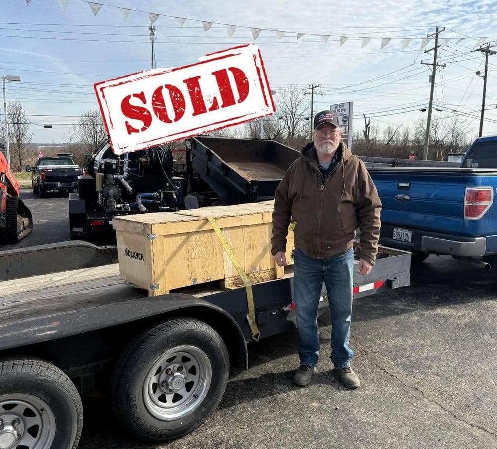 Man standing beside a trailer with a sold crate, showcasing a recent purchase.