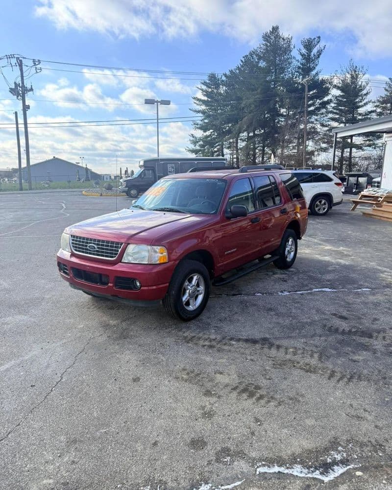 Red SUV parked in a lot with trees and blue sky in the background, showcasing a clean exterior.
