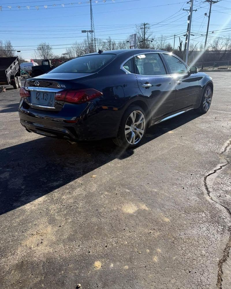 Black Infiniti Q70L parked, showcasing sleek design and alloy wheels on asphalt.